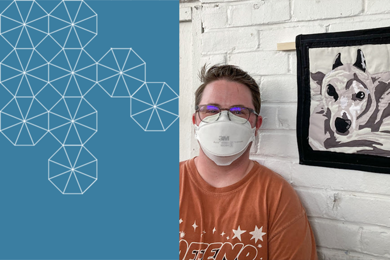 Kris smiling, wearing a white mask and orange shirt before a white brick wall with a quilted portrait of their dog