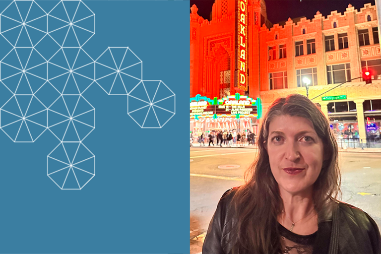 Megan smiling towards the camera, in the evening in front of the Fox Theater in downtown Oakland, with a blue box with white tessallations to her left