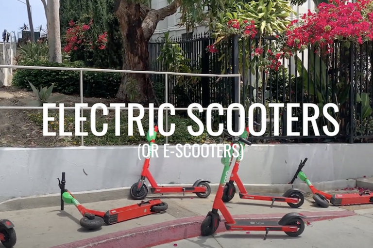 A group of six Lime scooters on a sidewalk in Oakland with the subtitle "Electric Scooters (or E-Scooters)" in the foreground