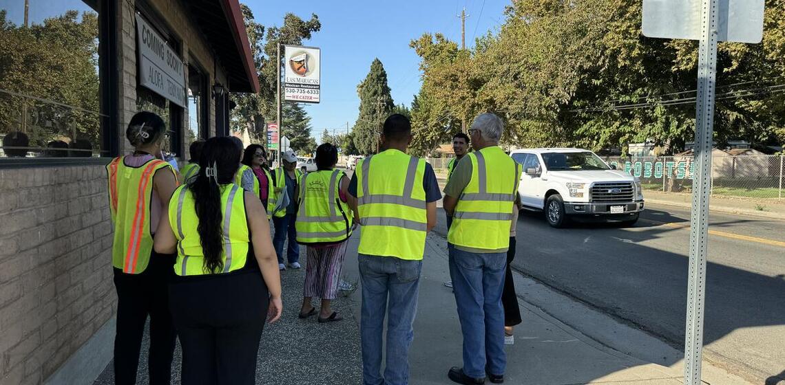 Adults wearing safety vests listen to an instructor leading the group.