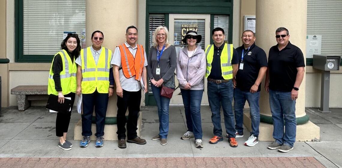 Adults wearing safety vests pose for a photo during a site visit.