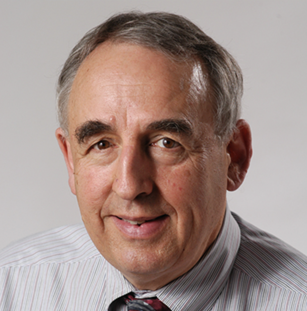 David R. Ragland, smiling in a light grey striped shirt with tie