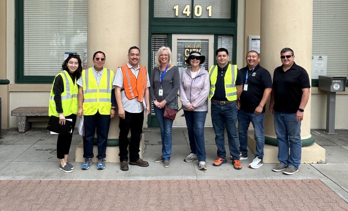  Adults wearing safety vests pose for a photo during a site visit.