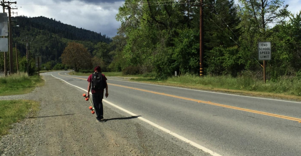 Young man with skateboard on Hoopa Valley Indian Reservation road