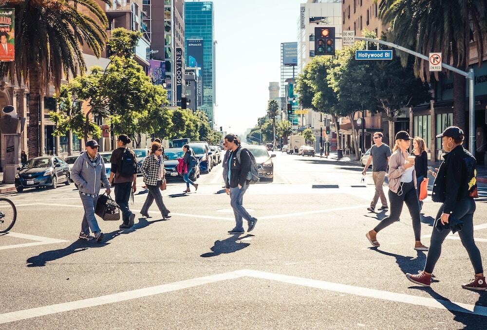 People walking, biking across an intersection on Hollywood Blvd. in Los Angeles on a sunny day