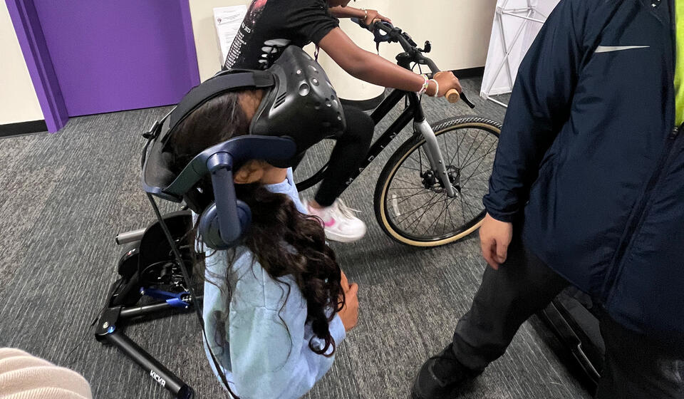 Two innovators at the Self-e-STEM summer camp participate in the bicycle simulator activity